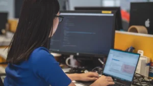 Mujer trabajando en oficina con dos computadoras
