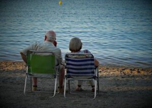 Pareja de ancianos sentados en la playa disfrutando del mar
