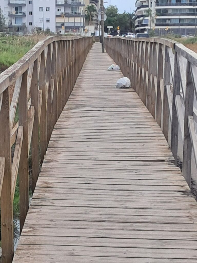 Bolsas de basura en la pasarela de madera de ses Feixes de Talamanca.